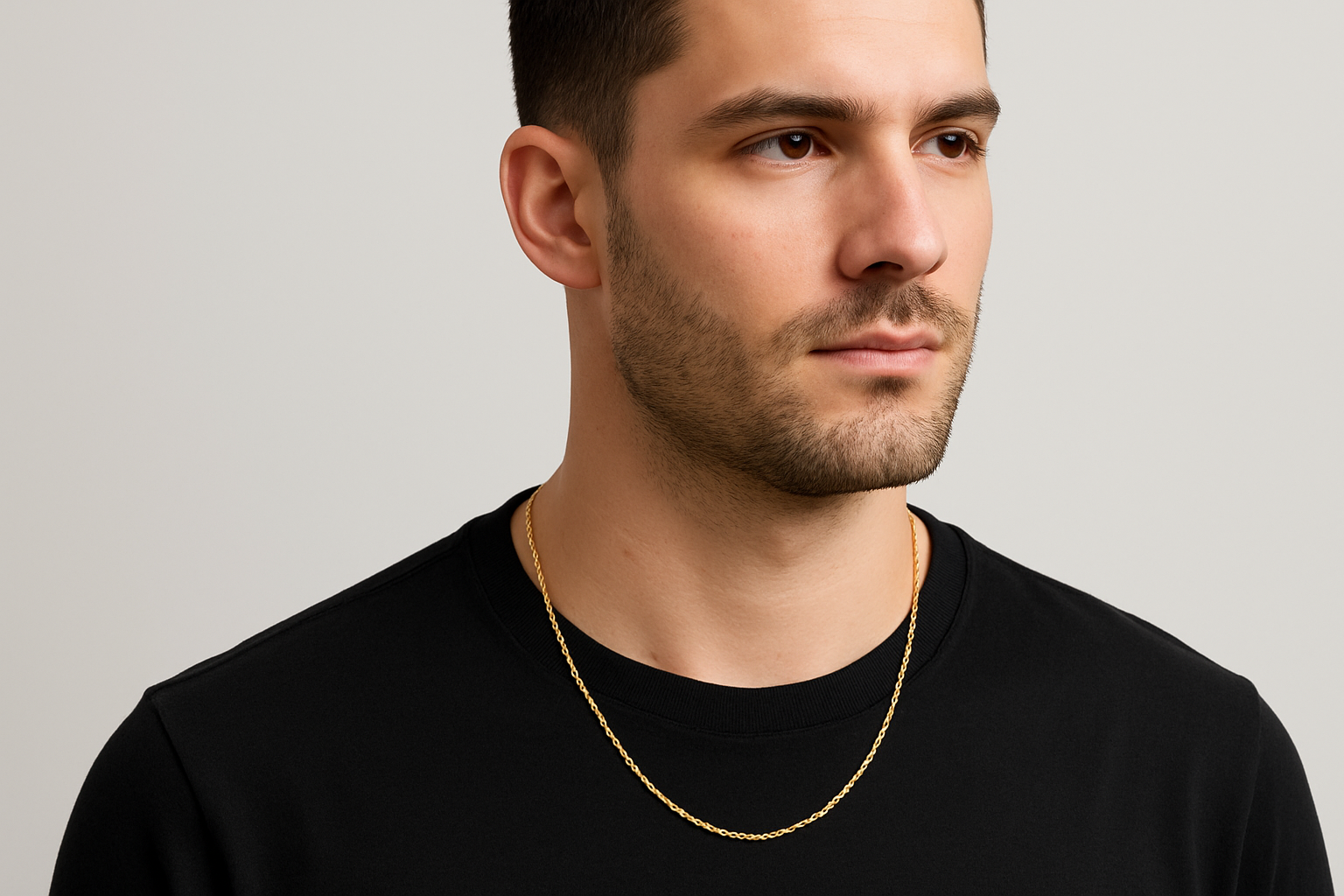man wearing thin gold rope chain. light gray bacdkground. man aligned to the right