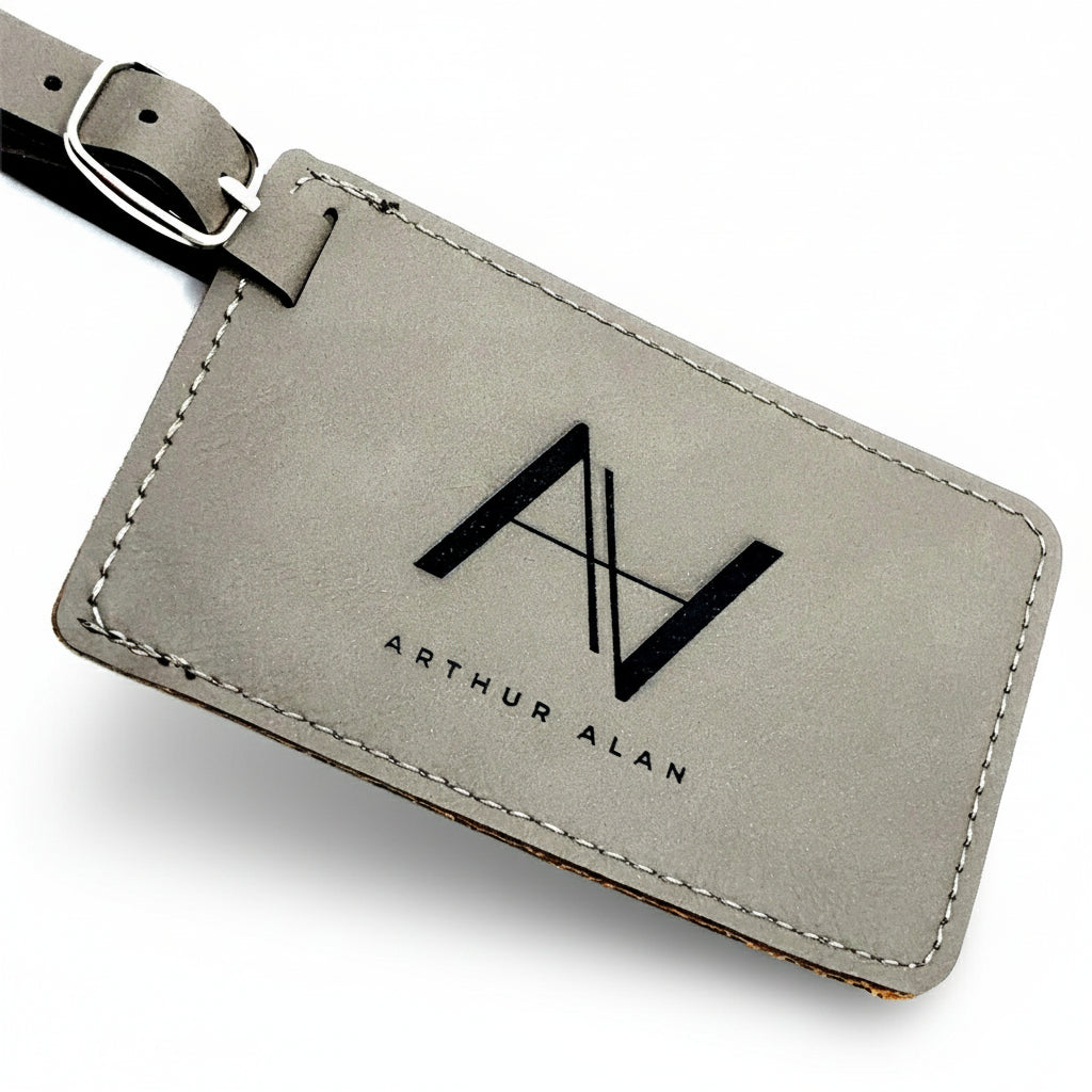 Gray leather luggage tag with 'Arthur Alan' branding on a white background