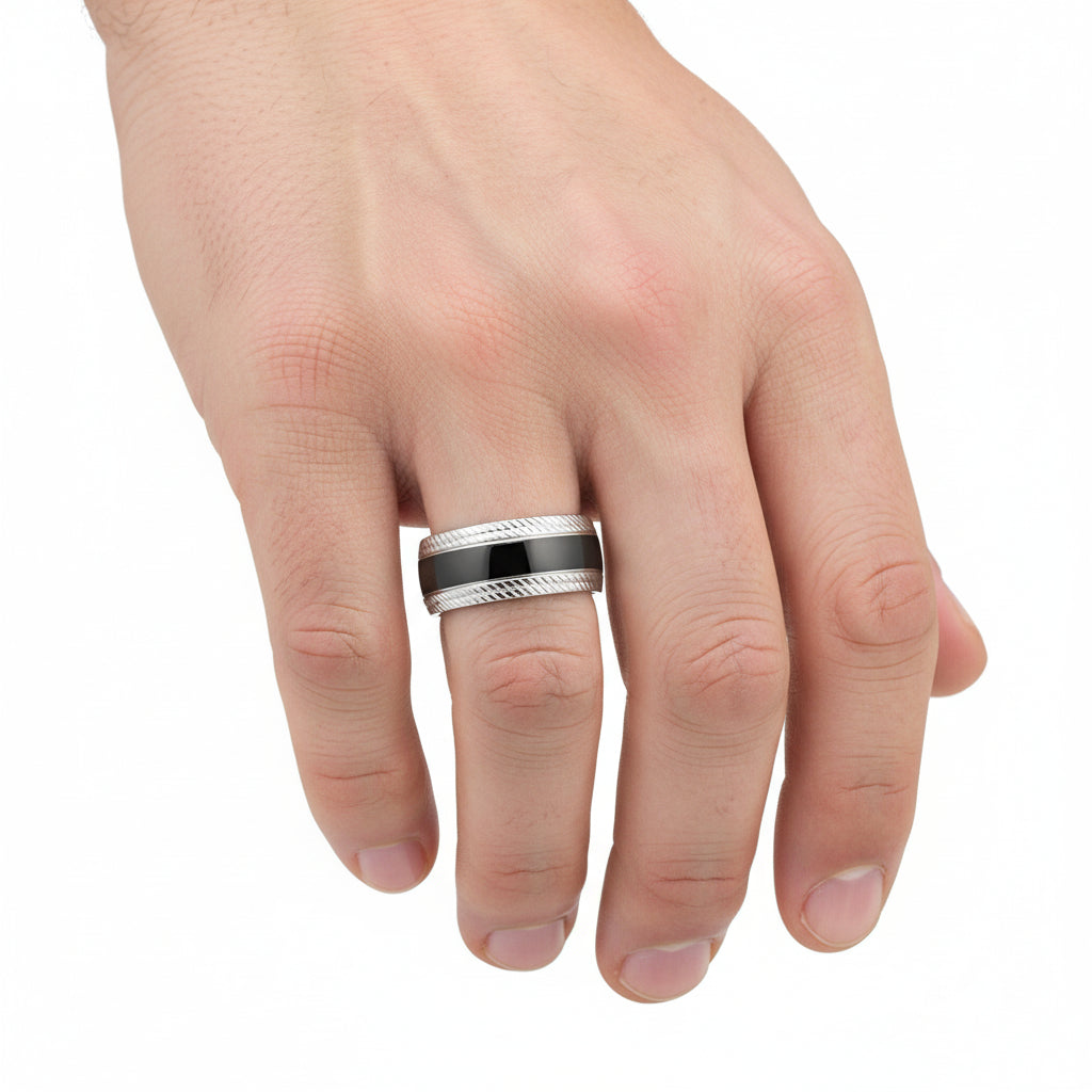Silver ring with a black band on a person's finger against a white background