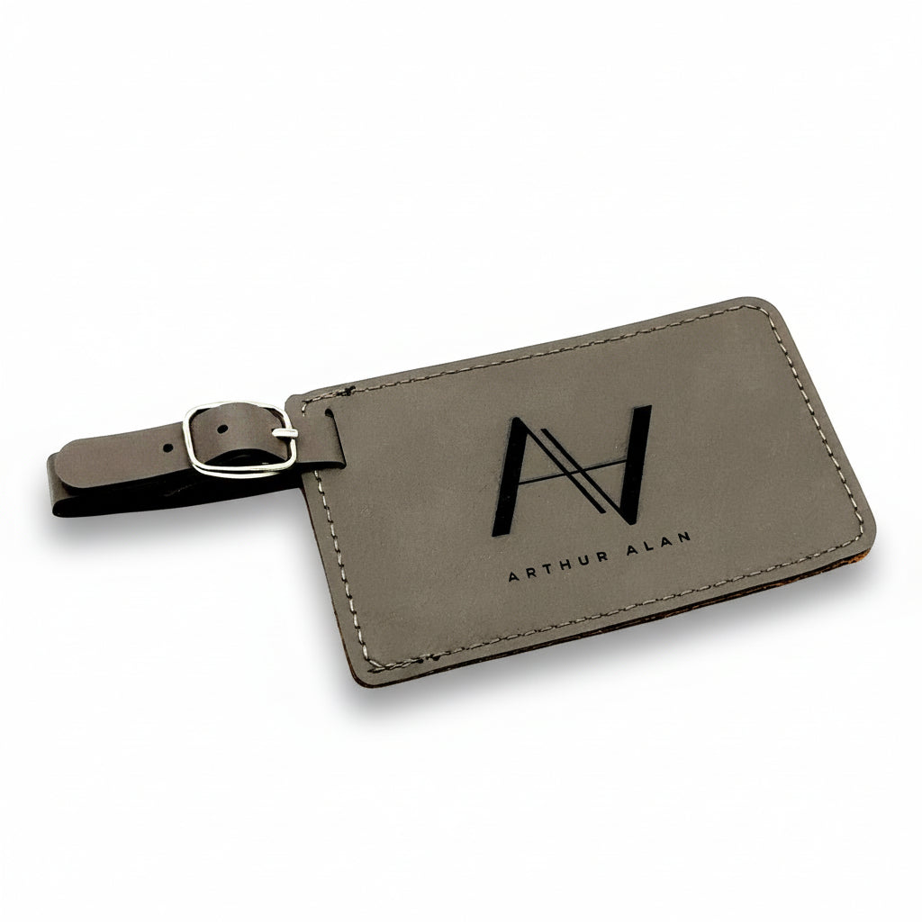Gray leather luggage tag with 'Arthur Alan' branding on a white background
